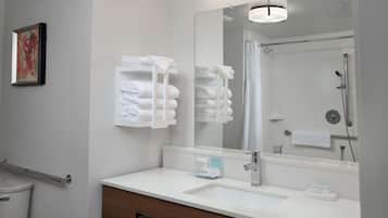 A modern bathroom with a white sink, mirror, and towel rack.