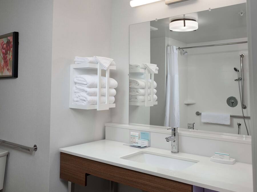 A modern bathroom with a white sink, mirror, and towel rack.