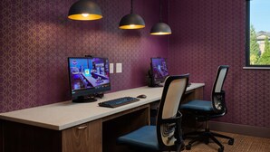 A room with purple patterned wallpaper, two computer monitors, a keyboard, and two office chairs. - Hampton Inn Sherwood Portland (Sherwood)