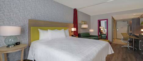 Una habitación de hotel con una cama grande, un escritorio, una silla y un sofá pequeño.