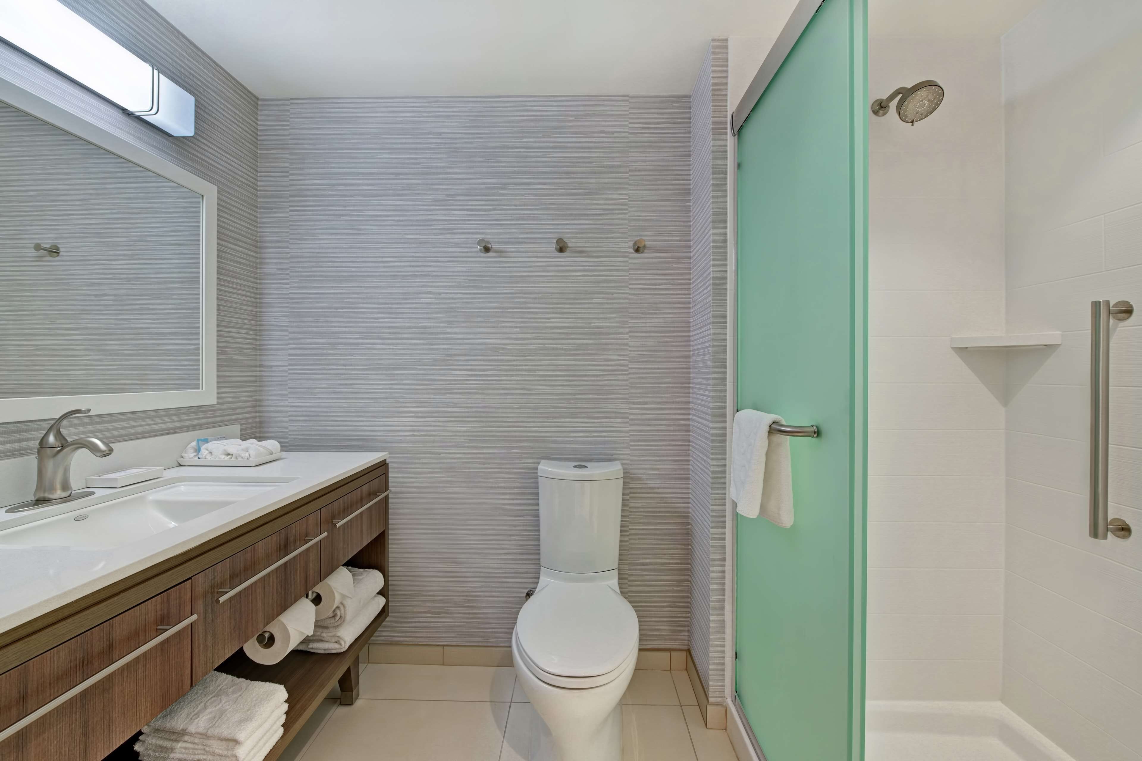 Un baño moderno con lavamanos, tocador, inodoro y ducha.