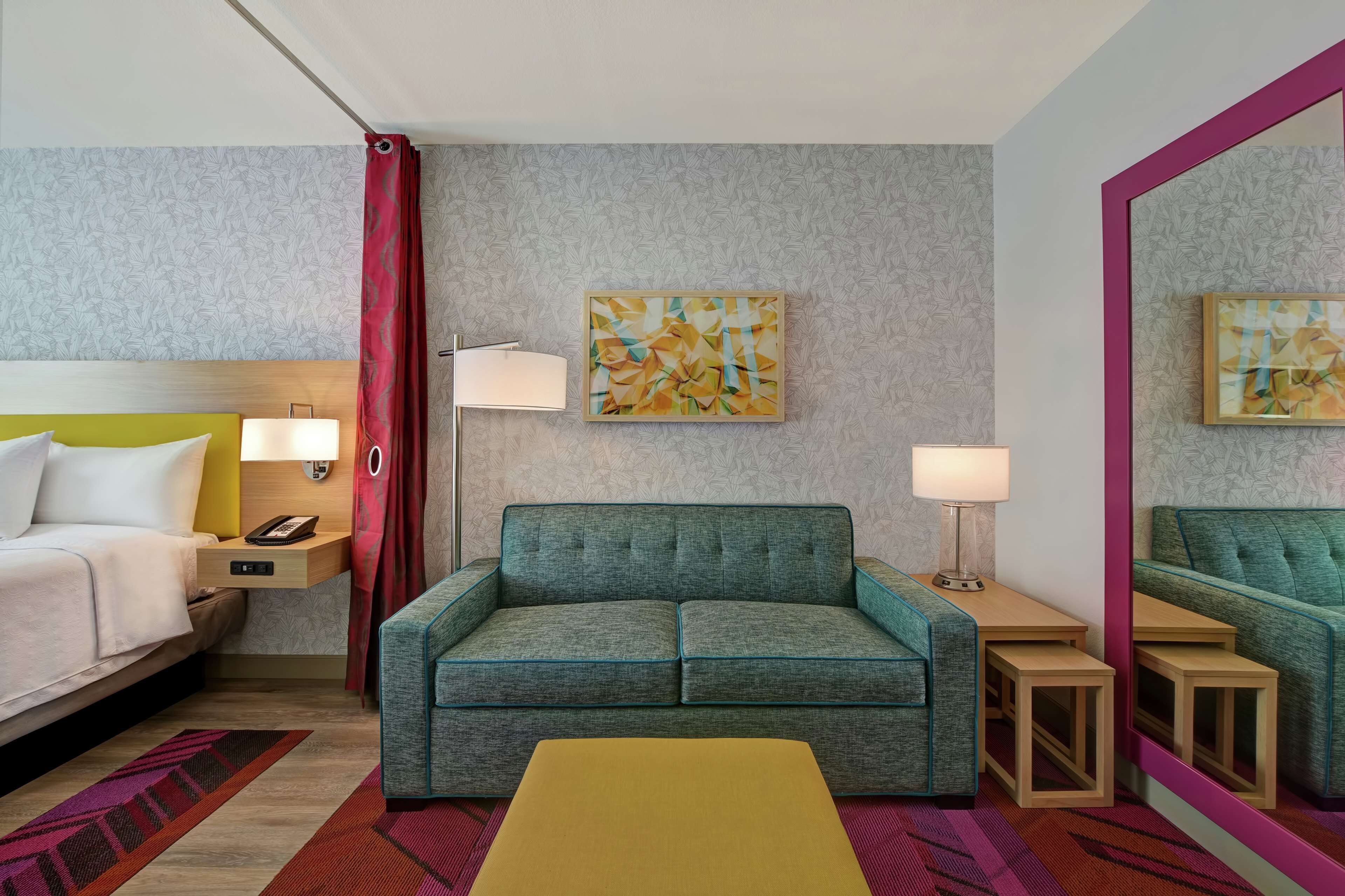 Ein Hotelzimmer mit einem Bett, einer Schlafcouch, einem kleinen Tisch, einem Spiegel und zwei Wandleuchten.