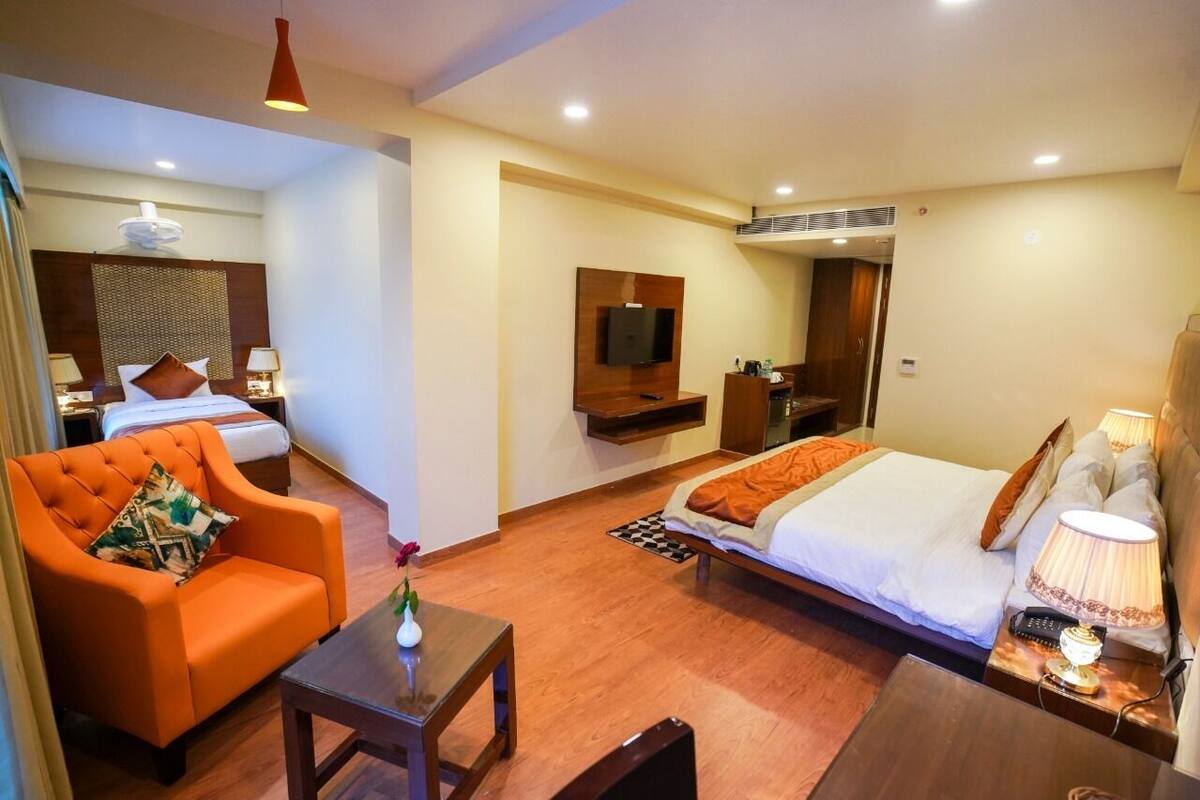 A hotel room with a bed, a sofa, a TV, a desk, and a mirror.