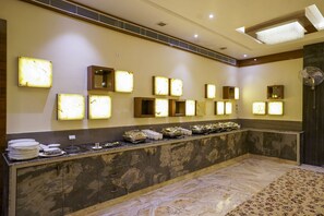 Un espace d’accueil d’hôtel avec un comptoir en marbre, des luminaires fixés au mur et une moquette à motifs.