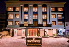 Un hôtel à plusieurs étages, doté d’une entrée imposante, de grandes fenêtres et d’une façade bien éclairée.