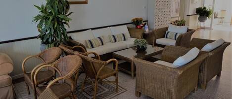 A cozy lounge area with wicker furniture, a sofa, and a coffee table.