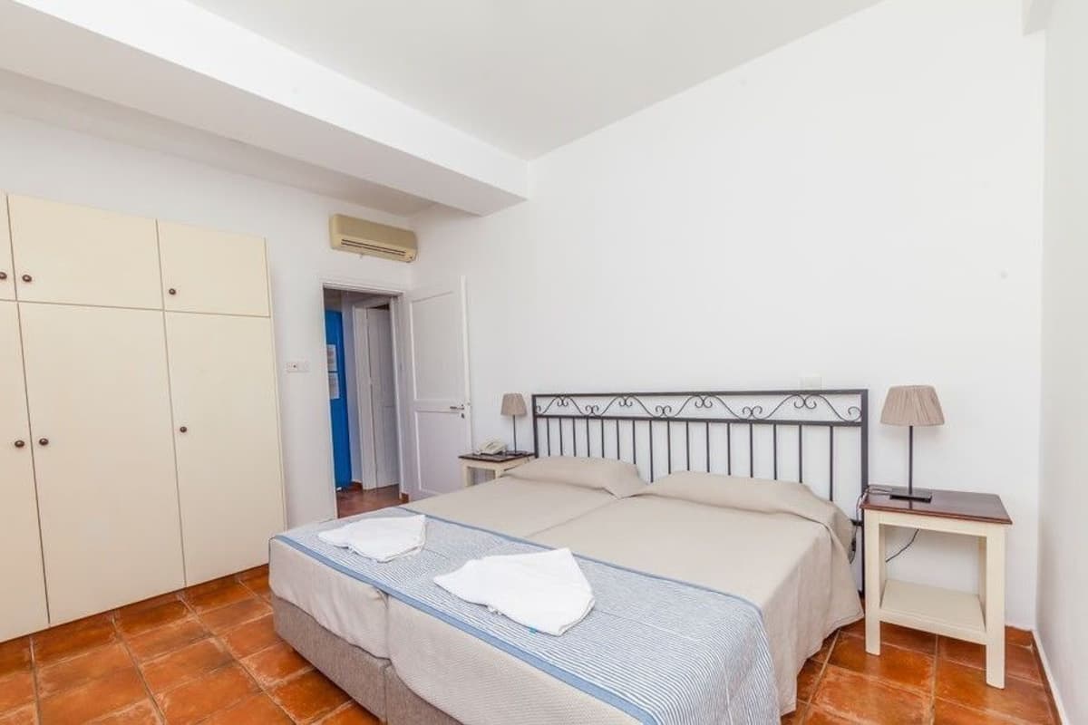 A bedroom with a bed, bedside tables, a wardrobe, and an air conditioning unit.