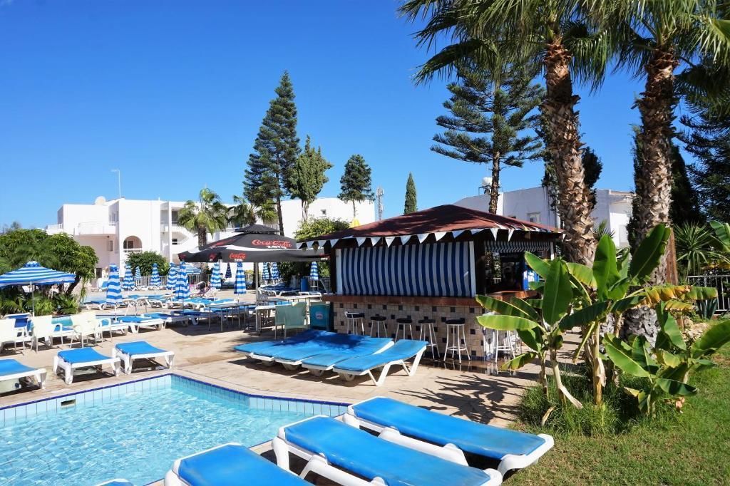 A pool area with lounge chairs, umbrellas, and a bar area with a Coca-Cola sign.