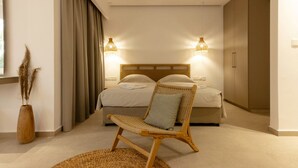 Une chambre à coucher avec un lit, une chaise en osier, une table de chevet et une fenêtre avec des rideaux.