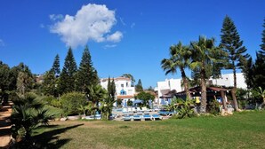 Un complexe hôtelier doté d’une piscine, de palmiers et de bâtiments en arrière-plan.