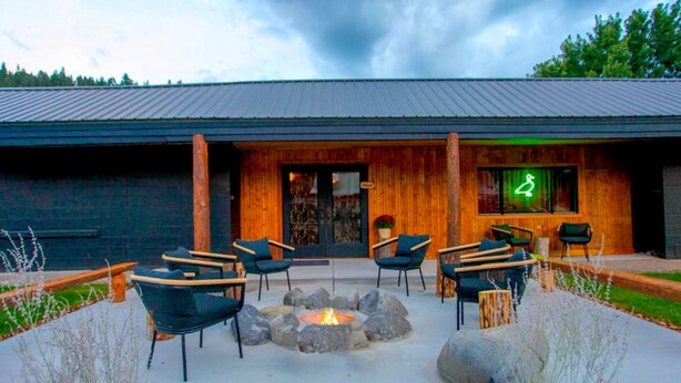 An outdoor seating area with fire pit, wooden chairs, and planters. - The Nightingale Motel (Pagosa Springs)