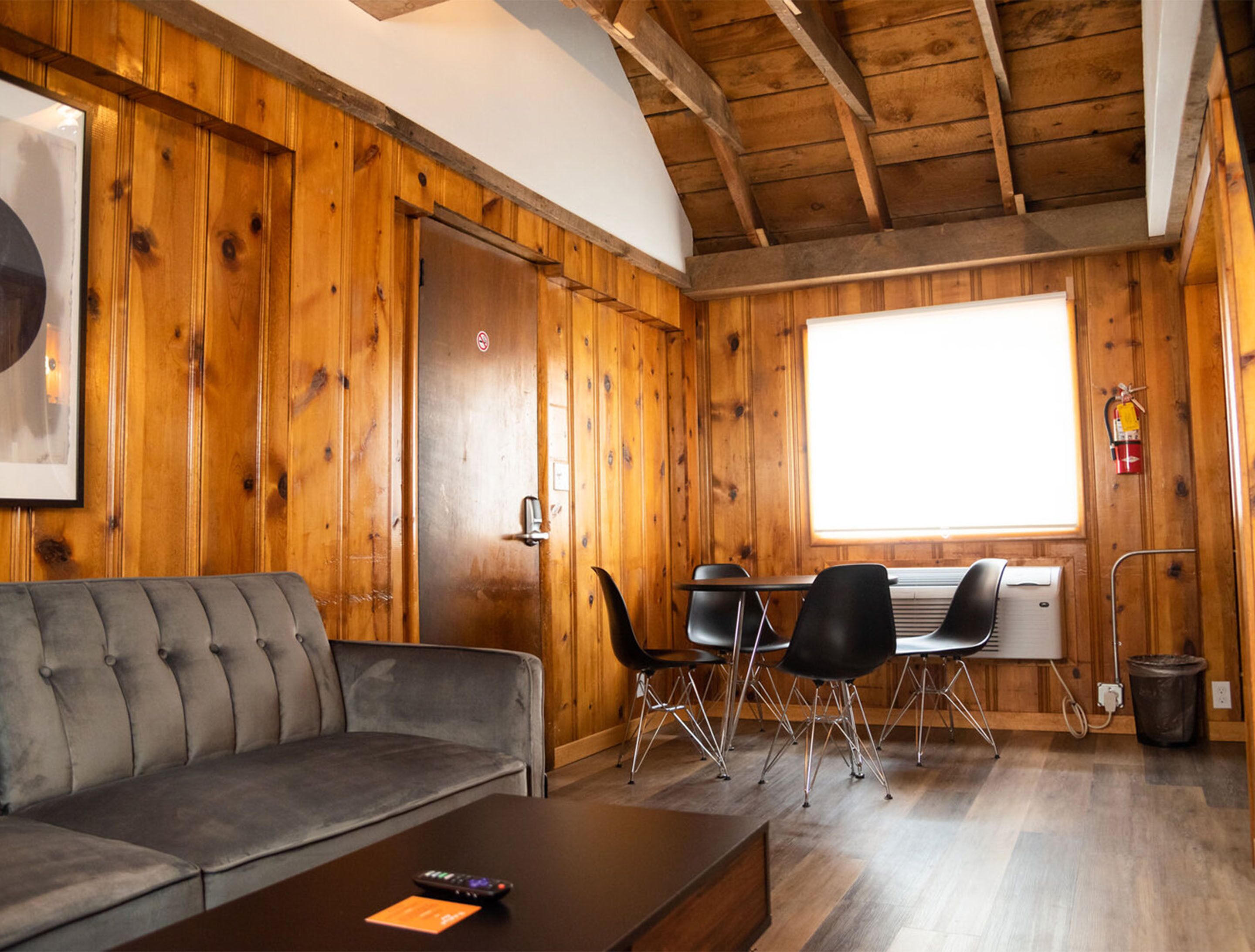 A cozy room with a wooden interior, a sofa, a table, and a window.