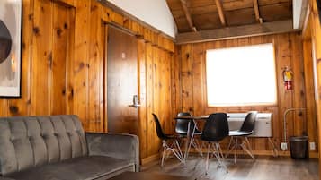 A cozy room with a wooden interior, a sofa, a table, and a window.