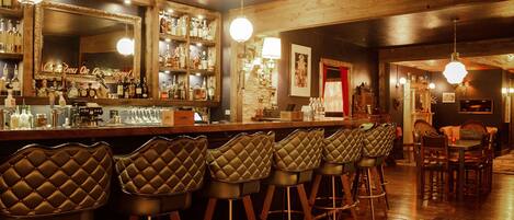 A bar area with multiple stools, a bar counter, and a mirror.
