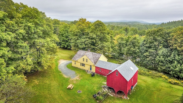 A rural property with a barn, a yellow house, and a well-maintained lawn.