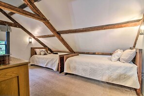 Een slaapkamer met twee bedden, houten balken, een nachtkastje en een raam met uitzicht.
