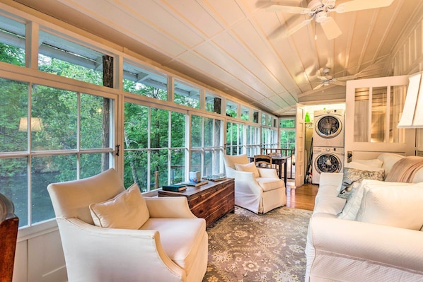 Relax in a spacious room with a high ceiling, large windows, and a comfortable seating area.