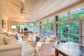 Relax in a spacious room with expansive views of the surrounding greenery, featuring a comfortable seating area and functional workspace.