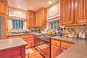 Enjoy cooking in this well-equipped kitchen with a central island, stove, microwave, and sink.