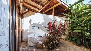 A spa area with a bathtub, surrounded by plants and a wooden structure.
