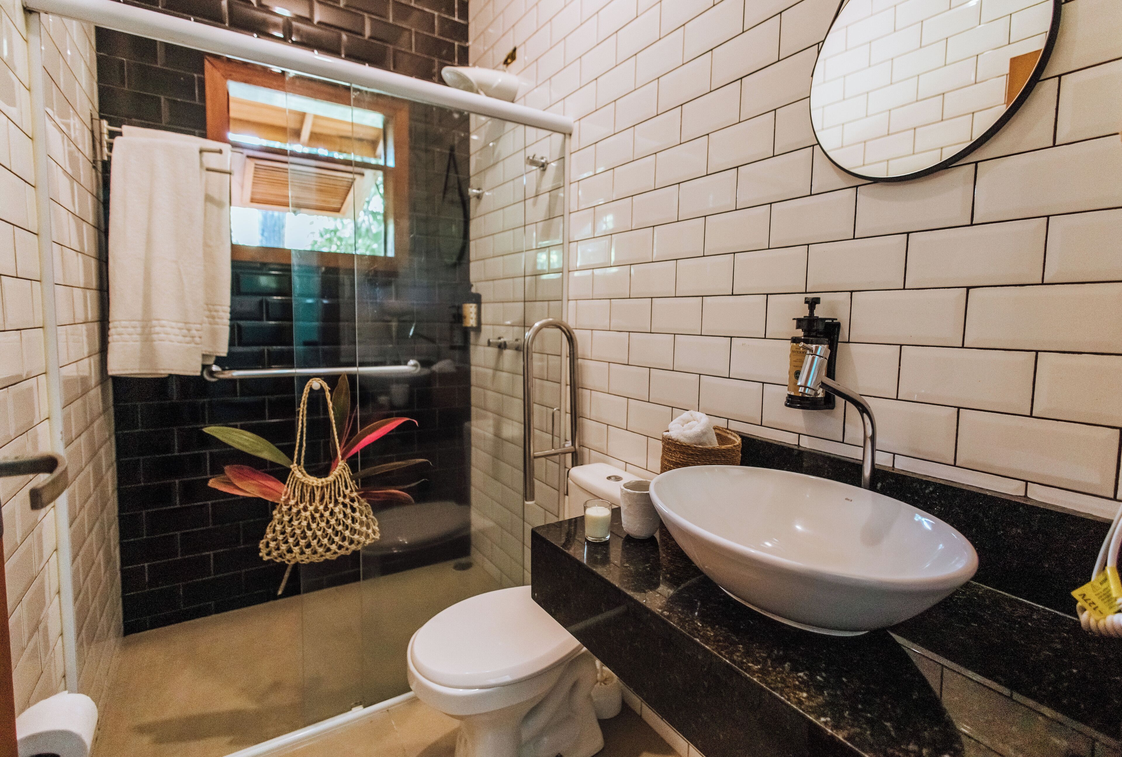 Un baño con inodoro blanco, un lavamanos grande y ducha con mampara de vidrio.