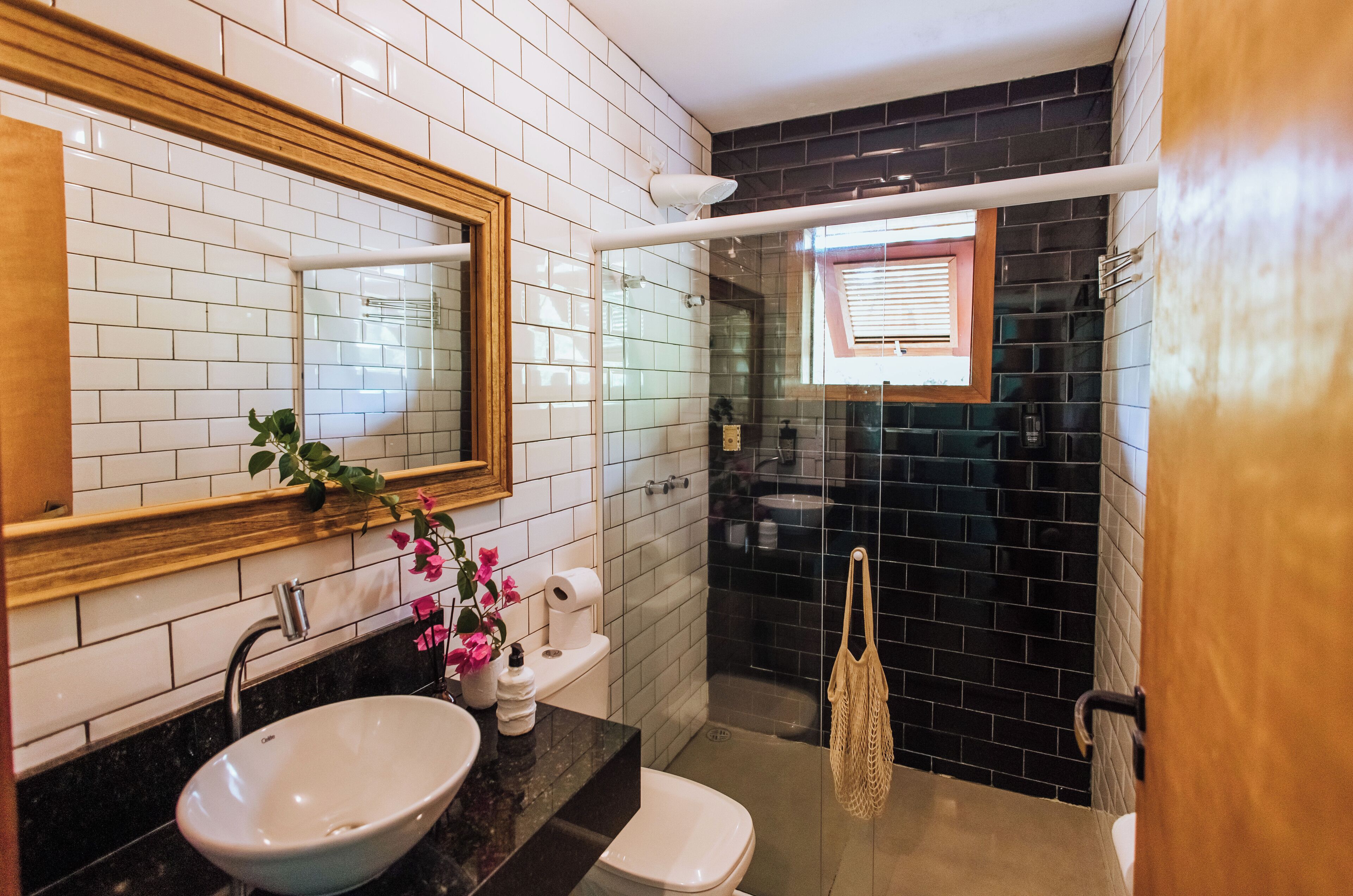 Un baño con lavamanos blanco, un espejo, inodoro y zona de ducha con toallero.