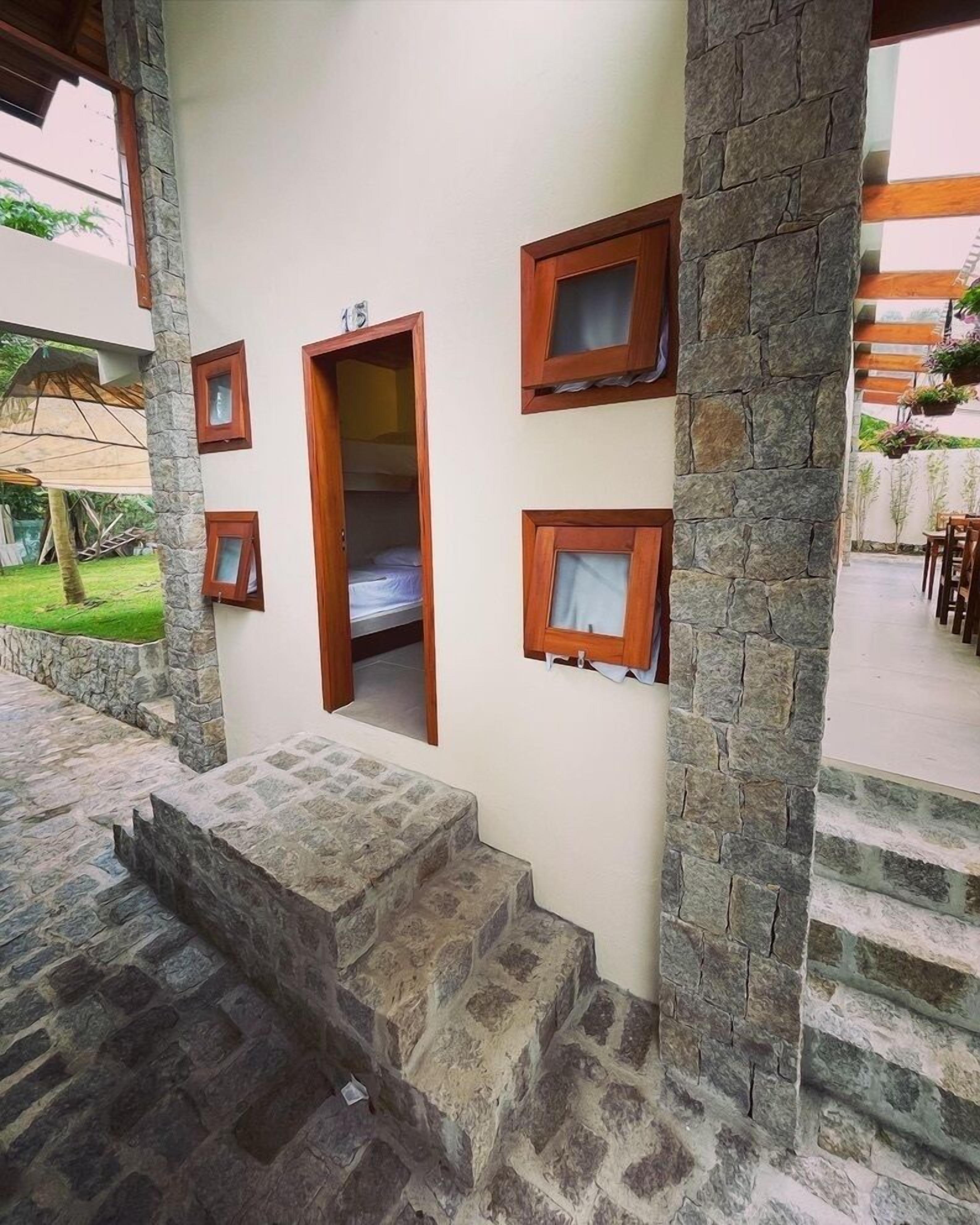 A room with a stone wall, a wooden door, and a small window.