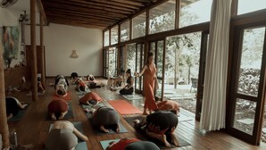 Un cours de yoga dans une salle dotée de grandes fenêtres et de planchers en bois.
