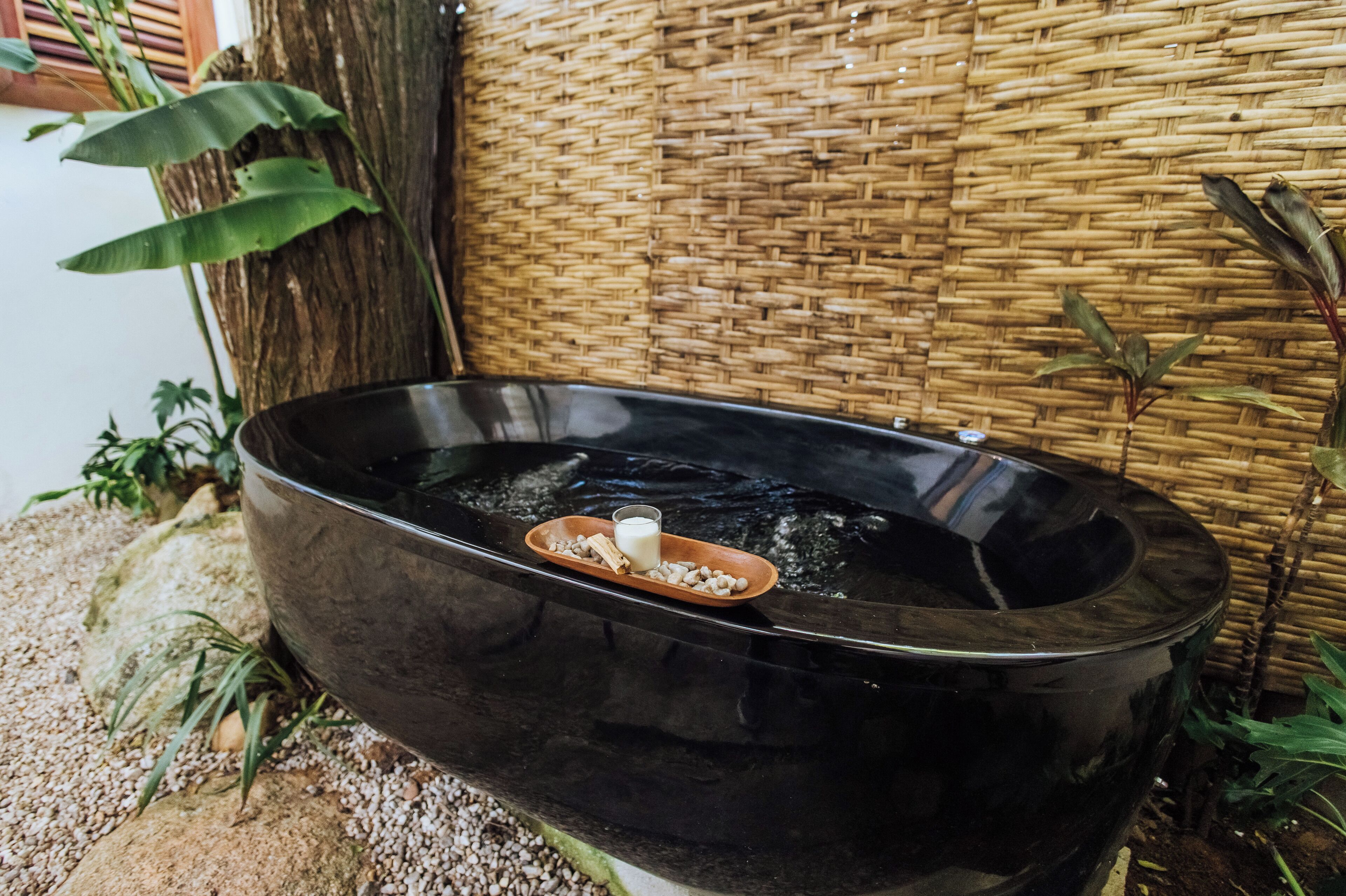 A black hot tub with a small tray containing a candle and a glass of water.