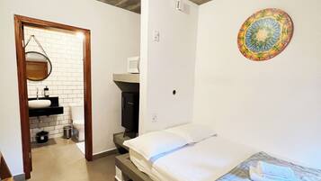 Un dormitorio con cama, una mesita de noche pequeña, un televisor montado en la pared y una lámpara de techo.