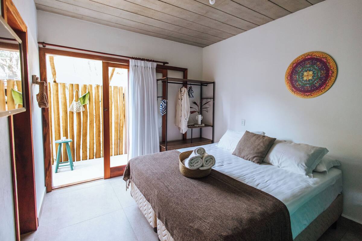 Un dormitorio con cama, techo de madera, pared blanca y un tapiz colorido.