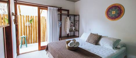 Un dormitorio con cama, techo de madera, pared blanca y un tapiz colorido.