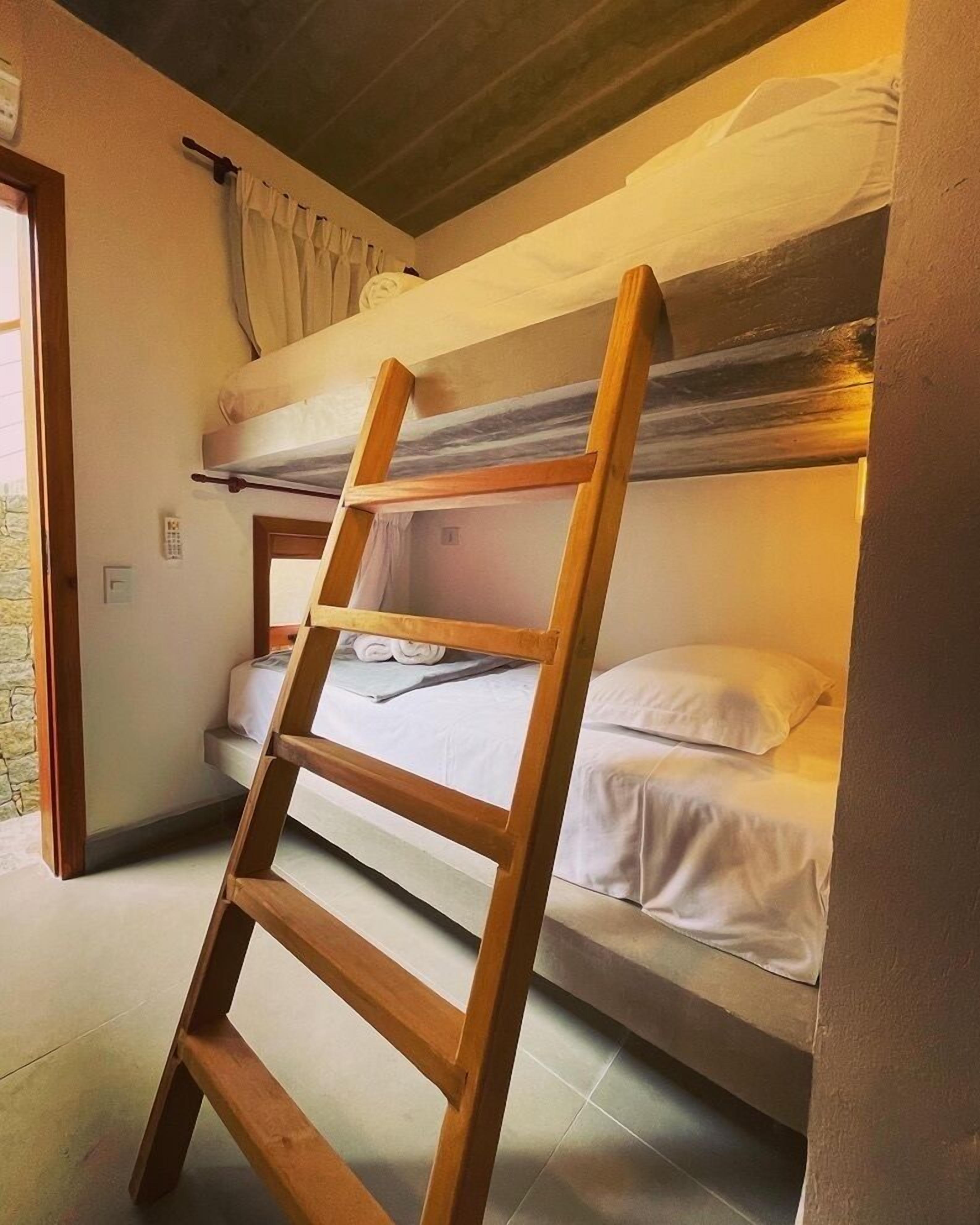 Habitación con literas y una escalera de madera.