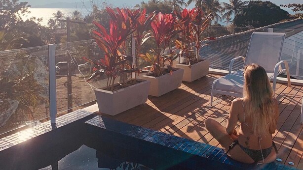 Un espace aménagé au bord de la piscine, offrant une vue sur les montagnes et un plan d’eau.