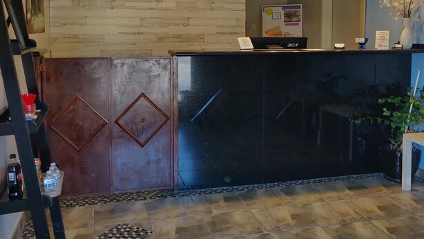 A reception desk with a 'WELCOME' sign, a phone, and a small desk with a laptop. - Travel Inn Delaware (Delaware)