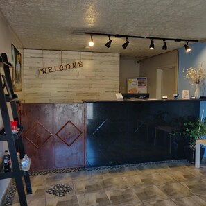 A reception desk with a 'WELCOME' sign, a phone, and a small desk with a laptop. - Travel Inn Delaware (Delaware)