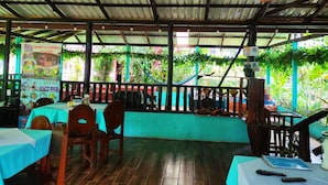 A restaurant with tables and chairs, a tiled floor, and a view of greenery outside. - Enjoy the Nature at Posada Río Celeste La Amistad (Costa Rica)