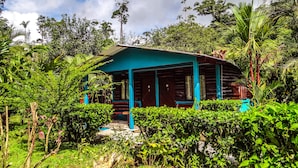 A small, single-story building with a blue roof and dark wooden walls, surrounded by lush greenery. - Enjoy the Nature at Posada Río Celeste La Amistad (Costa Rica)