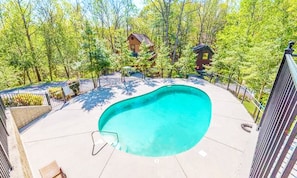 Piscina cercada por árvores e uma área com cerca.