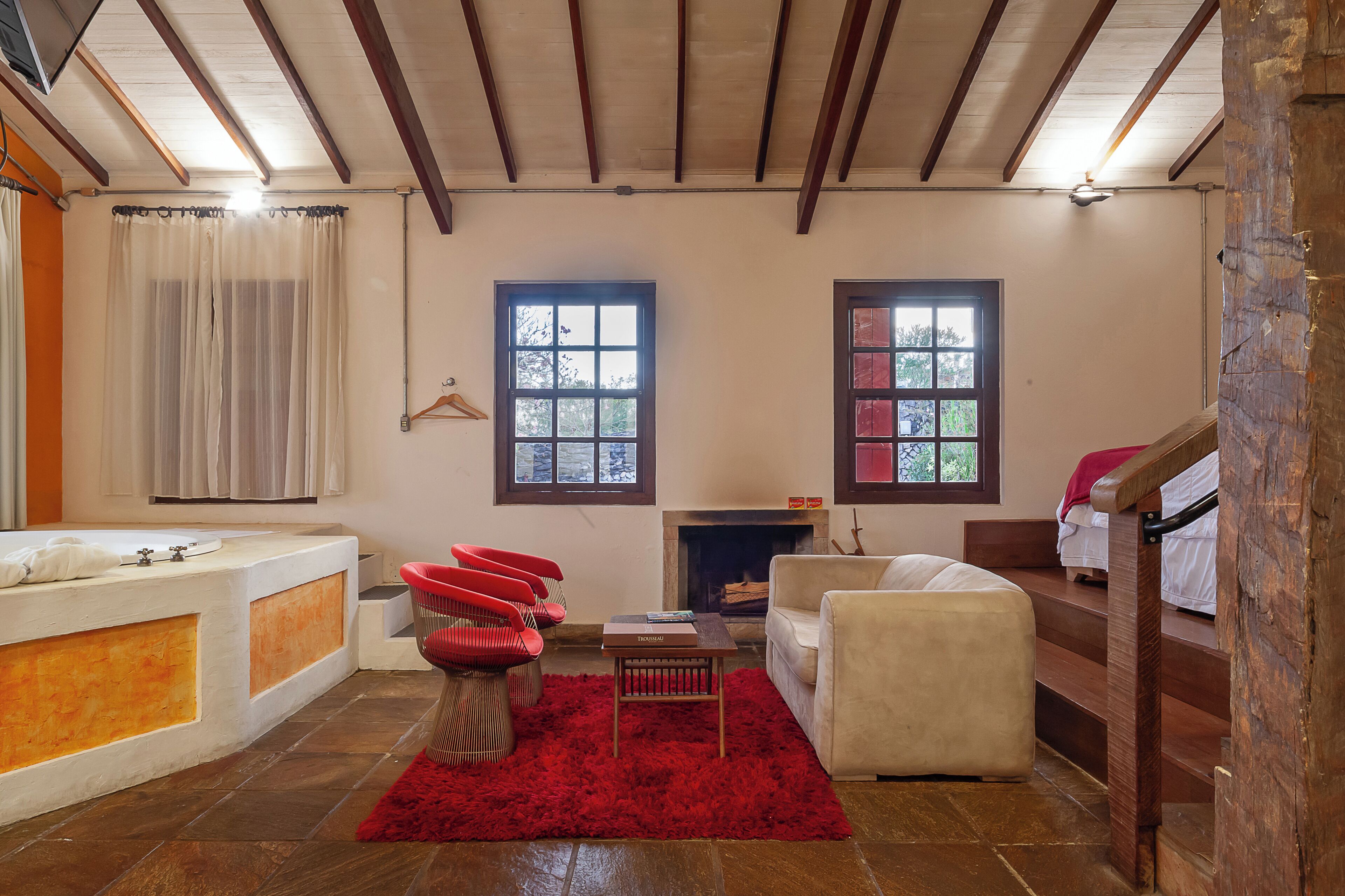 Una habitación con bañera, sillas rojas, chimenea y escalera.