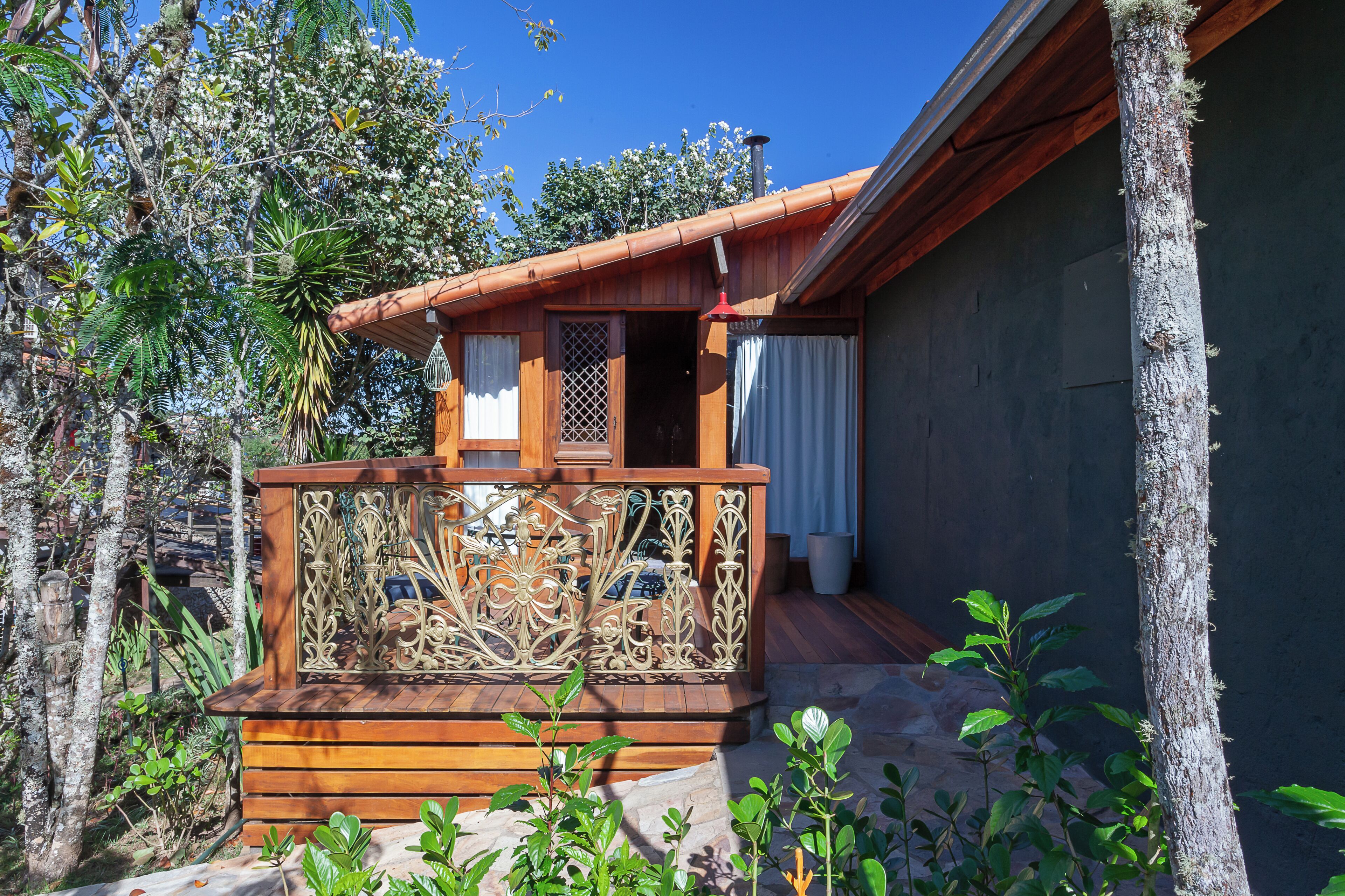 Une cabane en bois dotée d’un balcon, entourée d’arbres et de végétation.
