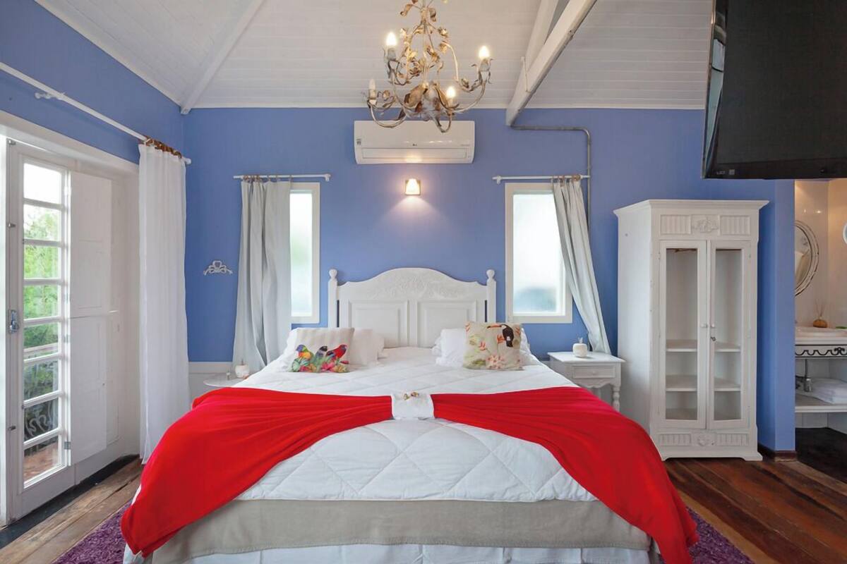 A bedroom with a bed, a chandelier, a wardrobe, and a television.