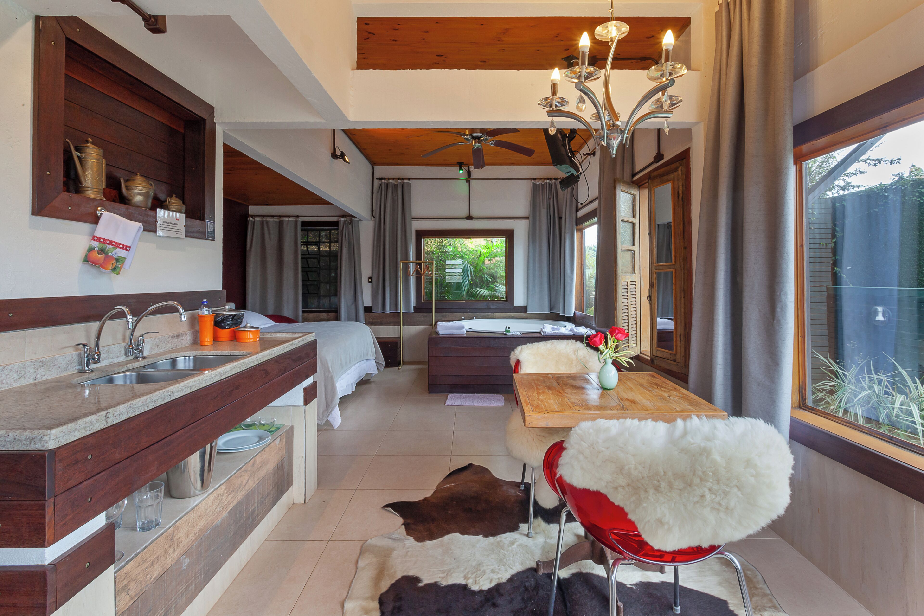 A modern kitchen with a wooden countertop, a dining area with a red chair, and a view of the outdoors.