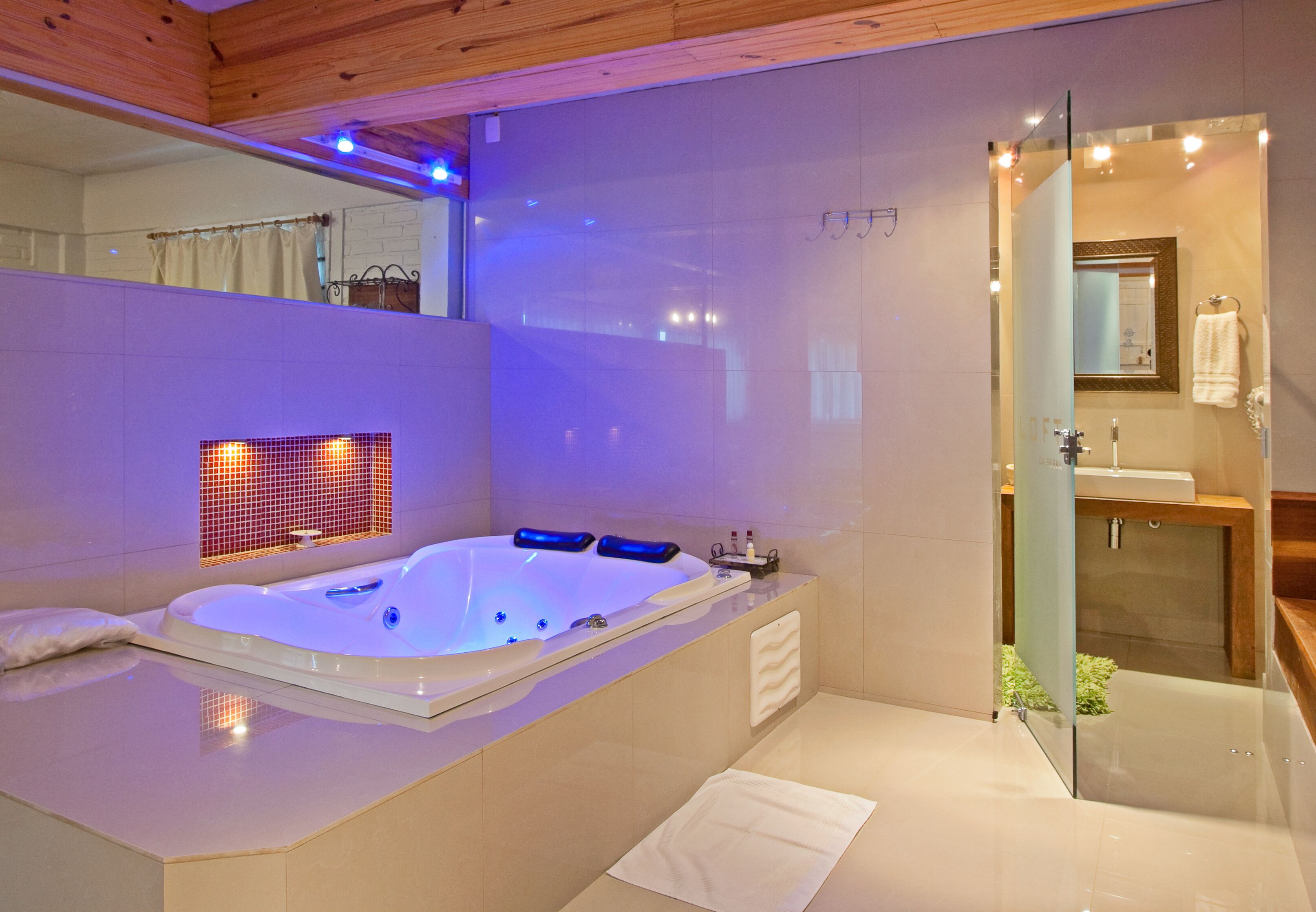 Un baño moderno con una bañera grande, cabina de ducha con mampara de vidrio y tocador con espejo.