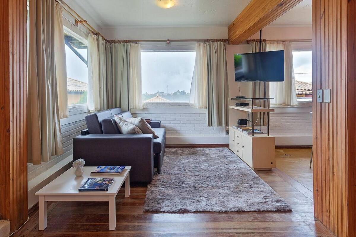 A cozy living room with a sofa, a coffee table, and a TV on a wooden stand.