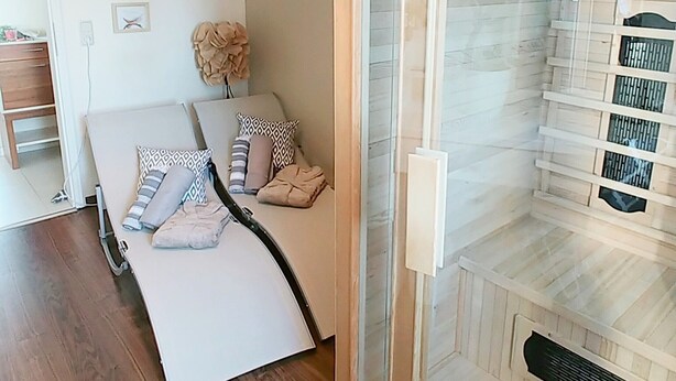A bedroom with a bed, a bedside table, a wall-mounted lamp, and a sliding glass door leading to a bathroom with a shower. - Feel-good time in the Zittau Mountains (Eichgraben)