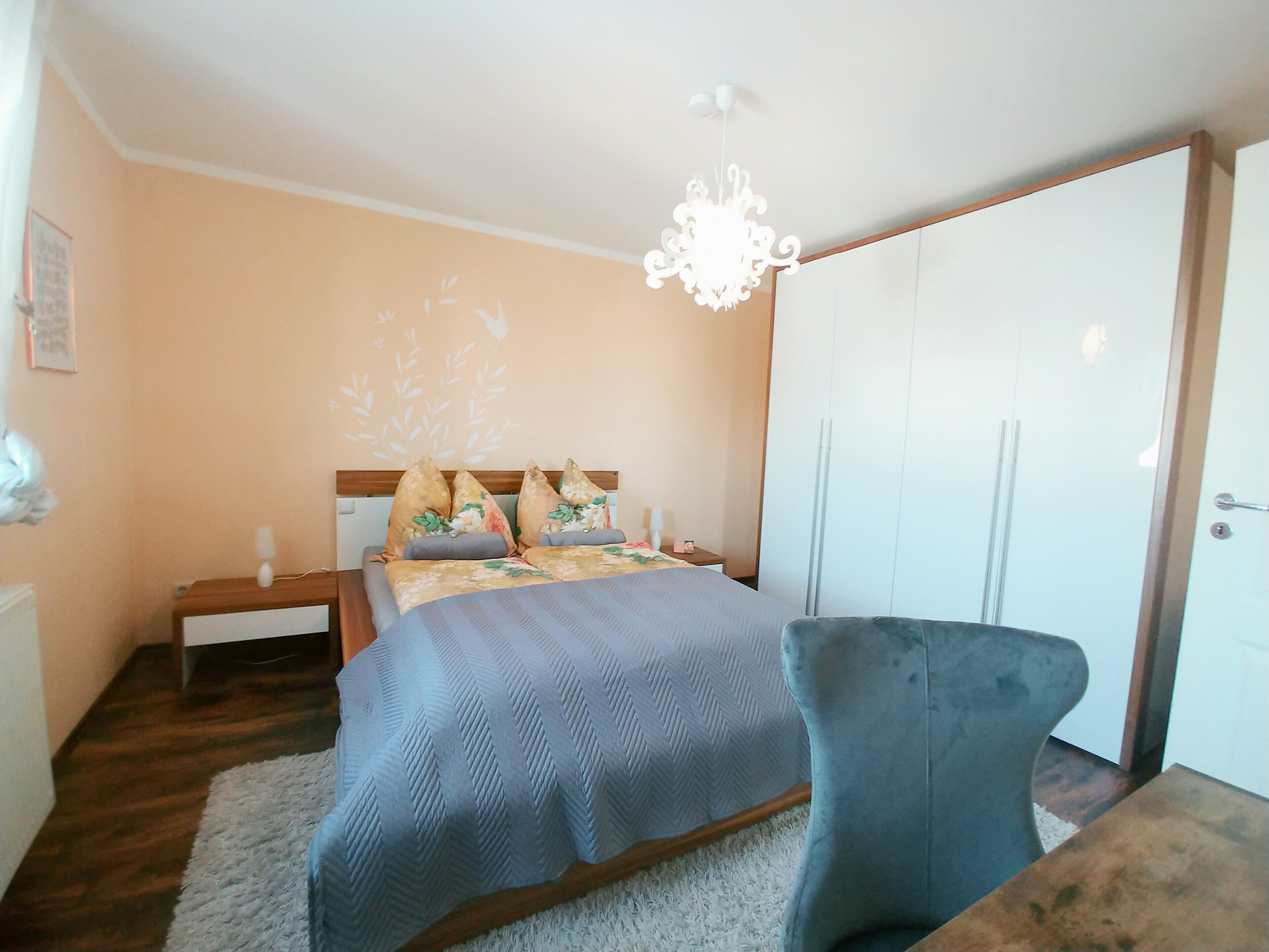 Une chambre à coucher comprenant un lit, une table de chevet, une commode, une chaise et une armoire.