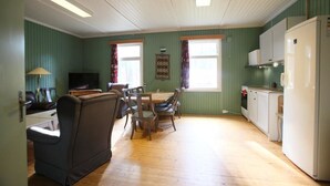 A compact living space with a dining area, a sofa, a television, and a kitchenette.