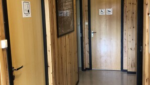 Corridoio con pareti e porte in legno, inclusi un cartello per la sauna, una porta accessibile in sedia a rotelle e un cartello che indica una zona fumatori.