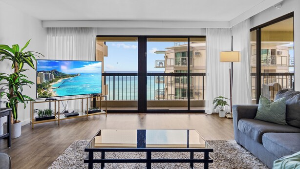 Ett modernt vardagsrum med en stor TV, en soffa, ett soffbord och utsikt över havet.